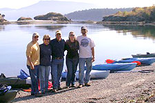 A small group of kayakers lands on a pebble beach on Sucia Island